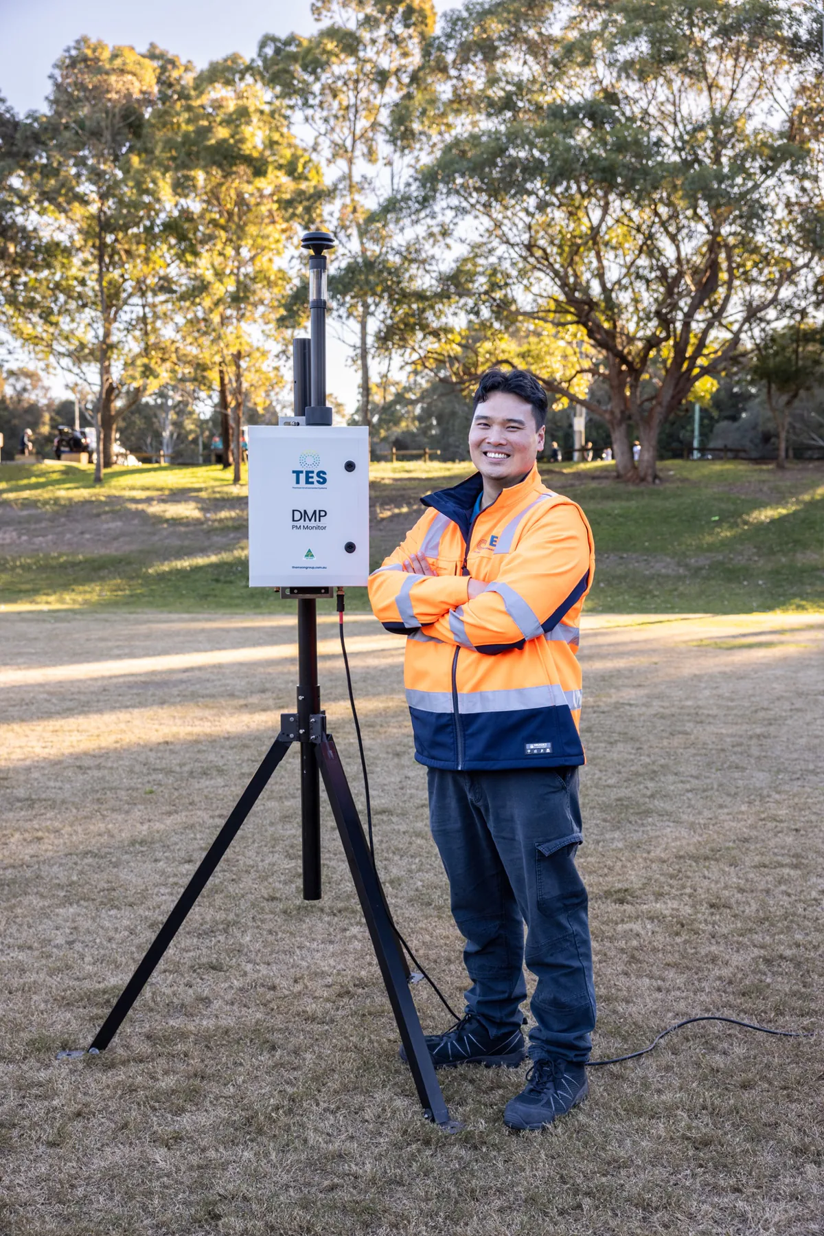 TES environmental monitoring specialist standing beside a DMP particulate monitor in the field